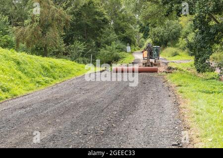 Une grande pelle de construction de couleur orange sur un chantier de construction de routes dans la campagne tchèque. Réparation de l'ancien pont. Travaux routiers. Banque D'Images
