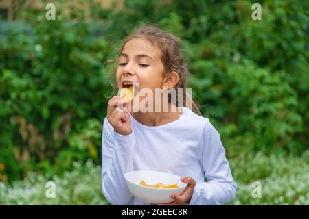 Un enfant mange des jetons dans la rue. Foyer sélectif.nourriture Banque D'Images