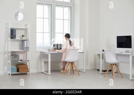 Femme d'affaires travaillant seule sur un ordinateur portable dans un bureau moderne et lumineux. Banque D'Images