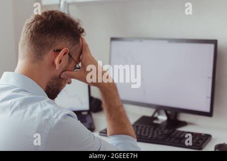 Contrarié homme investisseur-Trader devant des moniteurs avec des graphiques. Correction boursière. Chute de la crypto-monnaie. Marché baissier. Forex Banque D'Images