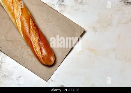 Baguette croquante sur papier sur fond en bois. Photo ci-dessus de pain de baguette française Banque D'Images