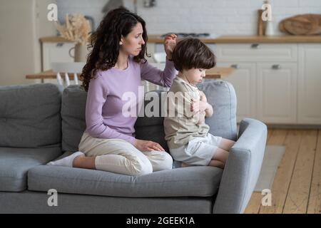 Excuant mère essayez de faire la paix avec têtu garçon offensé enfant frowning et ignorant la maman bienveillante Banque D'Images