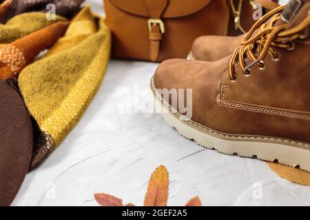 Sac en cuir orange pour femmes, chaussures brunes, foulard, feuilles d'automne sur fond gris. Accessoires tendance pour l'automne. Tenue confortable Banque D'Images