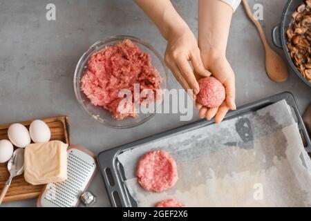 Femme préparant des côtelettes savoureuses dans la cuisine Banque D'Images