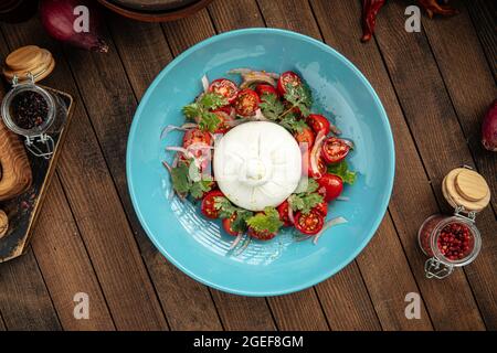 Salade de fromage burrata avec pommes de terre dans une assiette bleue Banque D'Images