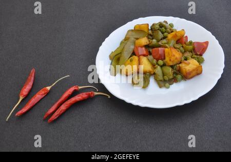 Cuisine indienne - plat de matar paneer mélange légumes recette et piments rouges sur fond noir avec espace négatif Banque D'Images