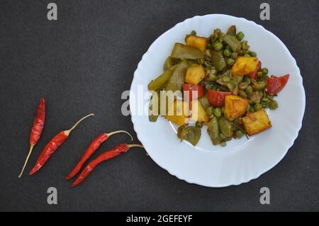 Cuisine indienne - plat de matar paneer mélange légumes recette et piments rouges sur fond noir avec espace négatif Banque D'Images