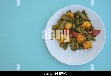 Photo du mélange de paneer matar veg (nourriture indienne) sur plaque blanche isolée sur fond bleu clair avec espace de copie Banque D'Images