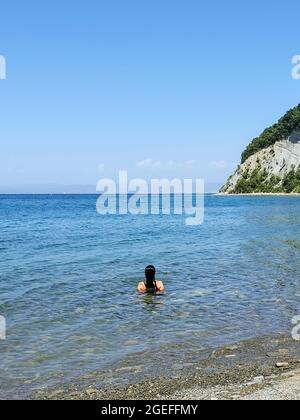 Vue arrière de la jeune femme se détendant en mer dans la baie de Moon à Strunjan, Slovénie. Banque D'Images