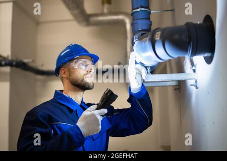 Inspection des tuyaux d'eau en PVC par un travailleur de la construction Banque D'Images