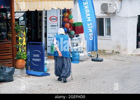 Urla, Izmir, Turquie - juin 2021 : femme âgée marchant avec sa canne vers une épicerie rurale dans le village de Bademler, Urla, Izmir, Turquie. Banque D'Images