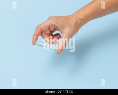 Main femelle avec ampoule et médicament sur fond bleu Banque D'Images