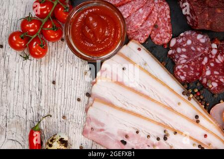 Trancher différents types de saucisses fumées et de viande sur un fond en bois. Vue du dessus Banque D'Images