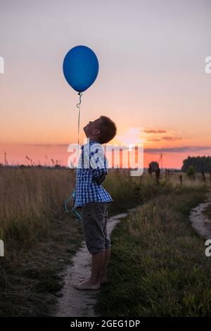 Joyeux anniversaire garçon avec des ballons colorés sur fond bleu ciel, des émotions sincères d'un joli enfant appréciant la vie Banque D'Images