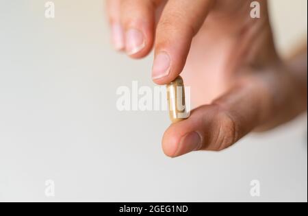 Gros plan avec une capsule d'herbe sur fond blanc. Concept de microdosage. Thérapie de psychédéliques. Dépression, traitement de l'anxiété Banque D'Images