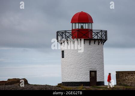 Port de Burry, Royaume-Uni. 20 août 2021. Ciel nuageux dans le port de Burry, dans l'ouest du pays de Galles pendant qu'une femme passe devant le phare. Crédit : Gruffydd Thomas/Alay Banque D'Images