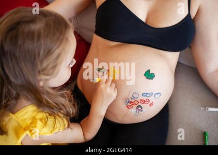 Jolie petite fille peinture sur ventre de femme enceinte Banque D'Images