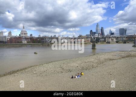 Londres, Angleterre, Royaume-Uni. Personnes sur la plage sur la rive sud de la Tamise à marée basse, en regardant vers la cathédrale St Paul et la ville de Londres Banque D'Images