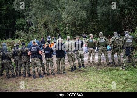 Des gardes-frontières sont vus pour protéger les réfugiés afghans à la frontière polonaise et biélorusse. Le nombre croissant de personnes qui tentent de traverser la Pologne transforme les migrations en une question politique intérieure en Pologne. Dans un village frontalier d'Usnarz Gorny, il y a un écart entre les gardes-frontières biélorusses et polonaises avec plus de 30 000 réfugiés afghans bloqués au milieu. Les réfugiés y sont restés depuis près de deux semaines car ils ne sont pas autorisés à entrer en Pologne ou à rentrer au Bélarus. Banque D'Images