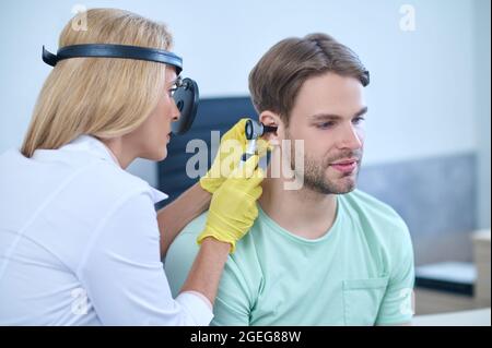 Médecin effectuant un examen otoscopique du canal auditif du patient Banque D'Images