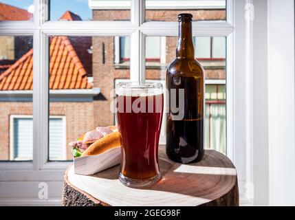 Boire de la bière foncée avec sandwich au poisson fumé à l'anguille avec vue sur la rue dans la vieille ville de Zierikzee, Zeeland, pays-Bas, gros plan Banque D'Images