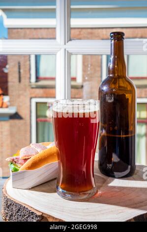 Boire de la bière foncée avec sandwich au poisson fumé à l'anguille avec vue sur la rue dans la vieille ville de Zierikzee, Zeeland, pays-Bas, gros plan Banque D'Images