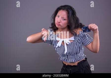 jolie femme chinoise montrant la carte de crédit avec les pouces vers le bas et le visage désapprouvant, Banque D'Images