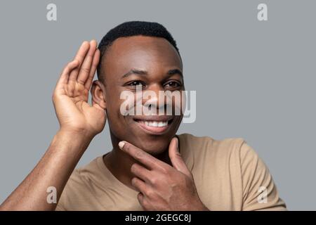 Homme souriant à la peau sombre à l'écoute des gossips Banque D'Images