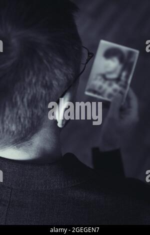 Vue arrière de l'adulte moyen regardant sur la photo de la femme. Banque D'Images
