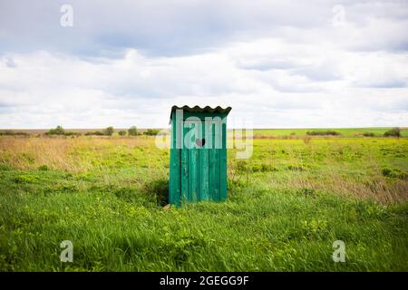 Vieux vert rustique toilettes avec un trou en forme de coeur dans les planches de porte. En plein air Banque D'Images