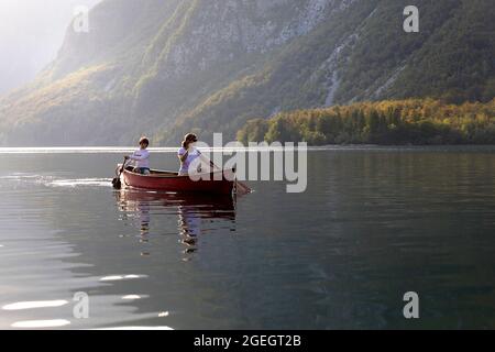 mère et fils lors d'une excursion en famille en pagayant dans un magnifique canoë rouge à la fin d'une journée d'été sur le lac bohinj en slovénie Banque D'Images