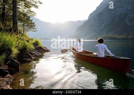 mère et fils pagayant dans un magnifique canoë rouge lors d'une journée d'été incroyable sur le lac bohinj en slovénie Banque D'Images
