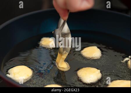 Délicieux et traditionnel sucré brésilien fait maison appelé BOLINHO DE CHUVA frits dans une poêle. Mettre la pâte à la main avec une cuillère. Banque D'Images