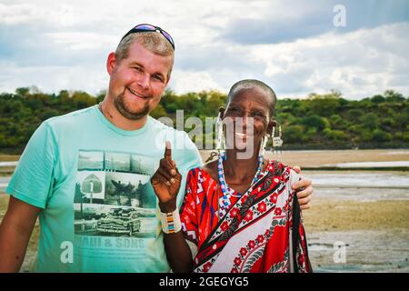 Une femme masai en vêtements traditionnels pose pour une photo avec un touriste Banque D'Images