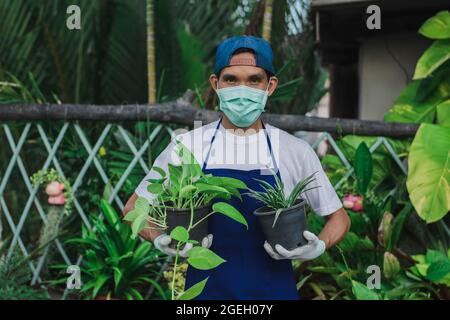 Homme jardin magasin propriétaire porter masque de visage travail floral magasin, masque protéger covid19 épidémie de coronavirus dans la boutique d'ornement de jardin Banque D'Images