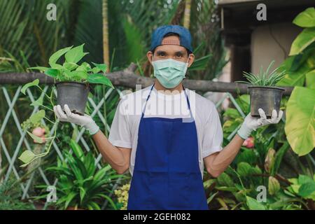 Homme jardin magasin propriétaire porter masque de visage travail floral magasin, masque protéger covid19 épidémie de coronavirus dans la boutique d'ornement de jardin Banque D'Images