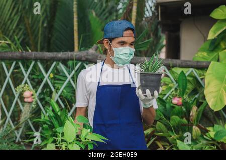 Homme jardin magasin propriétaire porter masque de visage travail floral magasin, masque protéger covid19 épidémie de coronavirus dans la boutique d'ornement de jardin Banque D'Images