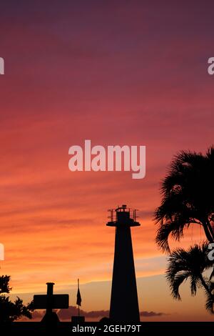 Un phare et un palmier silhouetté contre un ciel magnifique au crépuscule avec des roses, des oranges et des jaunes à Lahaina, Maui, Hawaii, États-Unis Banque D'Images