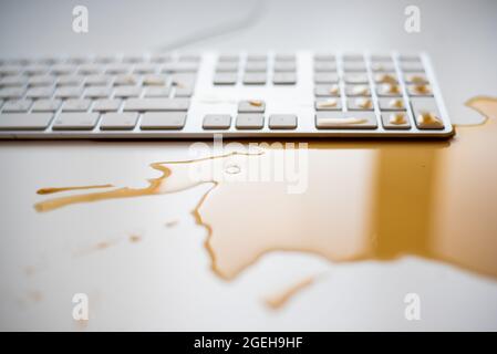 Projections de café noir sur un clavier d'ordinateur blanc Banque D'Images