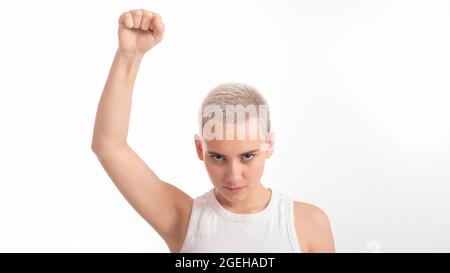 Jeune femme caucasienne tenant son poing sur un fond blanc. Une fille aux cheveux courts lutte pour les droits Banque D'Images