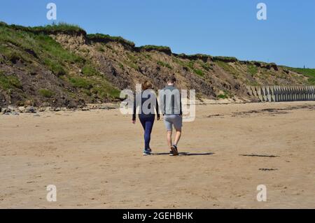 WHITLEY BAY. TYNE et WEAR. ANGLETERRE. 05-27-21. Le bech. Un jeune couple qui marche le long de la plage. Banque D'Images