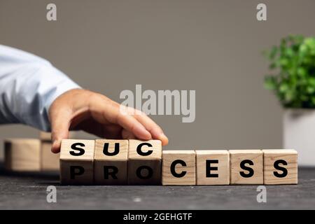 La main masculine fliping des cubes en bois avec le processus de mot au succès. CopySpace pour publicité, offre. Banque D'Images