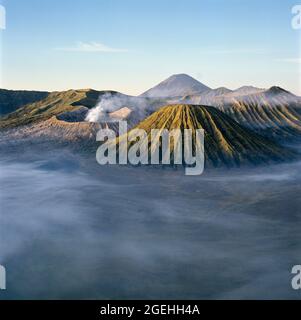 Soleil levant au-dessus du mont Bromo brumeux, parc national de Bromo Tengger Semeru, East Java, Java, Indonésie Banque D'Images