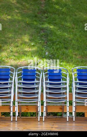 Des chaises métalliques empilées en piles et à côté d'un parasol dans un restaurant de rue, un café ou un centre récréatif. Les chaises sont sur le parquet. Rés Banque D'Images