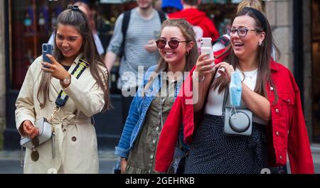 Édimbourg, Écosse, Royaume-Uni. 20 août 2021. Journée nuageuse pour le centre-ville et pour ceux qui cherchent un peu de divertissement des différents festivals de la ville. En photo : ces trois femmes venues d'Irlande utilisent leur téléphone mobile pour filmer Elvis alias Kevin Powell, qui apprécient sa représentation en tant que statue humaine sur le terrain de High Street au Edinburgh Fringe Festival. Crédit : Arch White/Alamy Live News Banque D'Images