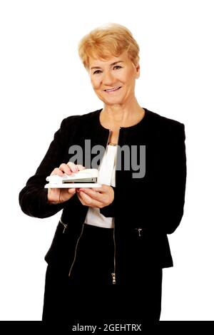 Employée de bureau caucasienne senior tenant une agrafeuse et souriant sur un fond blanc Banque D'Images