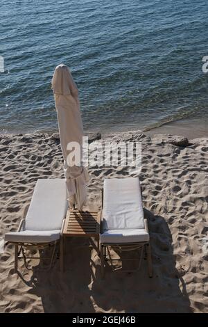 Vue sur deux chaises longues et un parasol en face d'une belle plage de sable en Grèce Banque D'Images