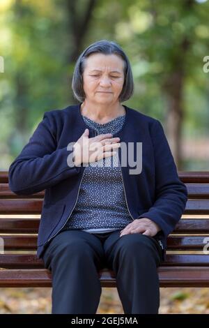 Femme vieillissante ayant une crise cardiaque. Une femme âgée s'empathe de sa poitrine dans la douleur aux premiers signes de l'angine ou d'un infarctus du myocarde ou d'une crise cardiaque, b supérieur Banque D'Images