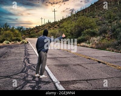 Arrière du jeune homme, hitchhiker attendant sur le bord de la route Banque D'Images