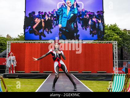 Édimbourg, Écosse, Royaume-Uni, 20 août 2021. Festival international du film d'Édimbourg : une performance d'artiste drag en avance sur la projection au Festival Theatre of the Amazon, film musical « Everybody’s Talking about Jamie ». Photo : latex (interprète) avec une scène du film sur un écran géant Banque D'Images